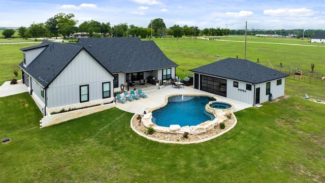 view of swimming pool with a patio area, a pool with connected hot tub, an outbuilding, and a yard