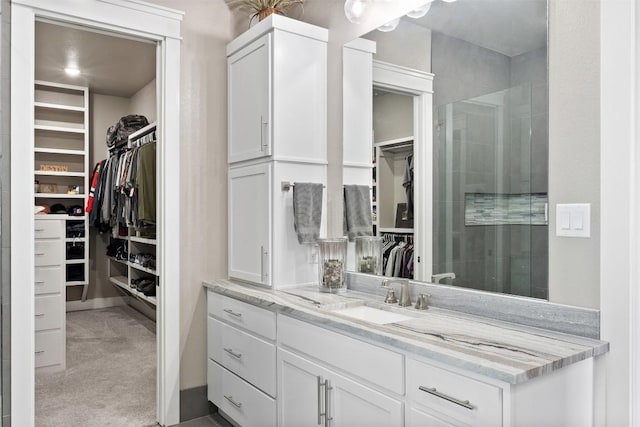 full bathroom featuring a walk in closet, tiled shower, and vanity