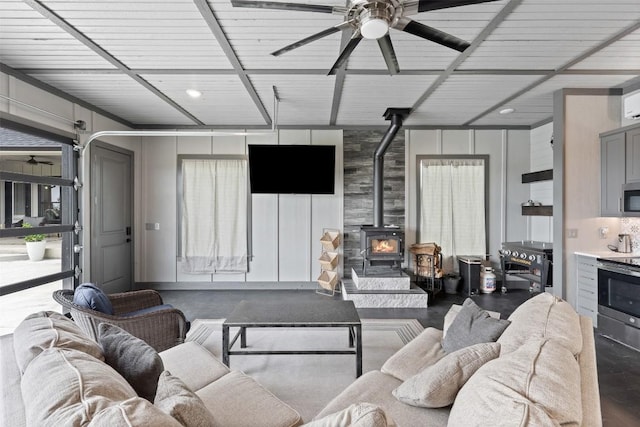 living room featuring a wood stove and ceiling fan