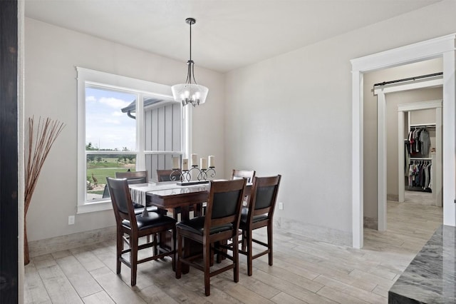 dining room with a notable chandelier, light wood-type flooring, and baseboards