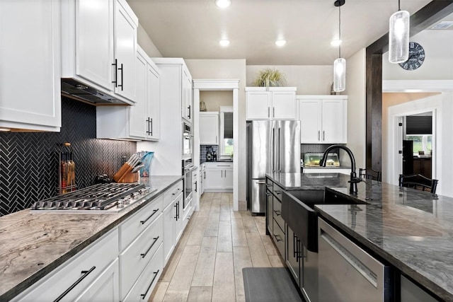 kitchen featuring white cabinetry, dark stone countertops, appliances with stainless steel finishes, and pendant lighting