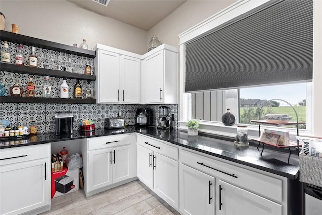 kitchen featuring open shelves, light wood-style flooring, dark stone counters, decorative backsplash, and white cabinetry