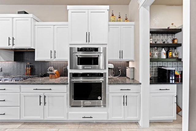 kitchen with backsplash, dark stone counters, white cabinets, stainless steel appliances, and open shelves