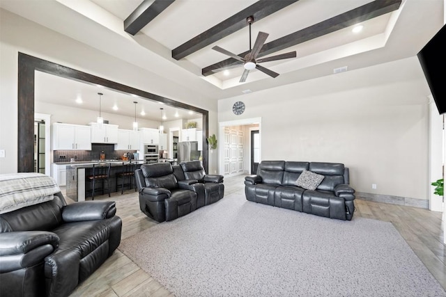 living room featuring beam ceiling, baseboards, light wood-style floors, and a ceiling fan