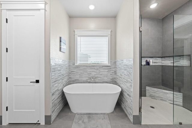 bathroom featuring wainscoting, a stall shower, tile walls, and a freestanding tub