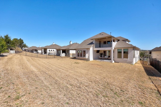 rear view of property featuring a fenced backyard, stucco siding, and a balcony