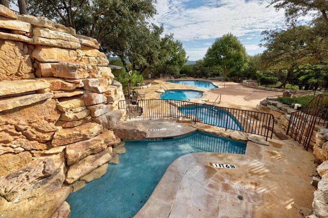 community pool with a patio, a community hot tub, and fence