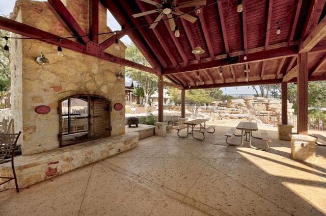 view of patio with ceiling fan and an outdoor stone fireplace