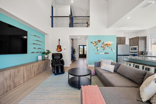 living room with visible vents, light wood-style floors, and a towering ceiling