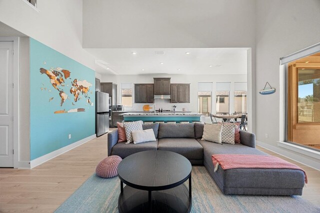 living area with light wood-style flooring, a high ceiling, and baseboards