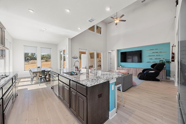 kitchen featuring light wood finished floors, visible vents, a kitchen breakfast bar, and a sink