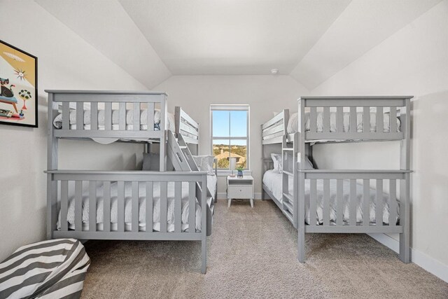 carpeted bedroom with baseboards and vaulted ceiling