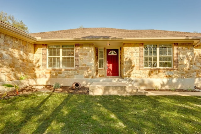 entrance to property with a lawn, stone siding, and a shingled roof