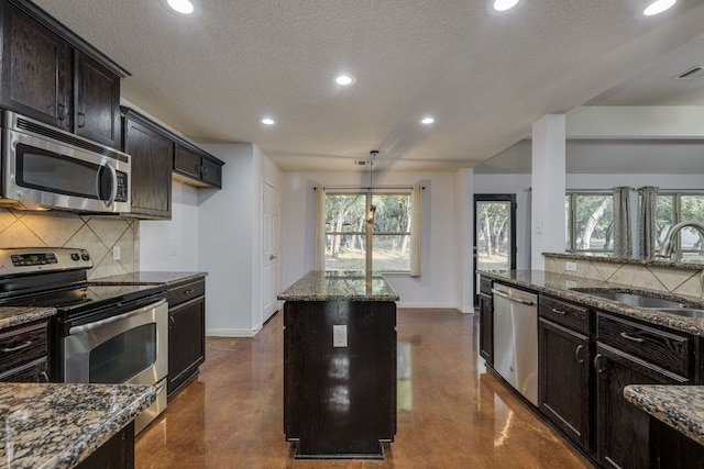 kitchen featuring concrete floors, dark stone counters, a sink, appliances with stainless steel finishes, and backsplash