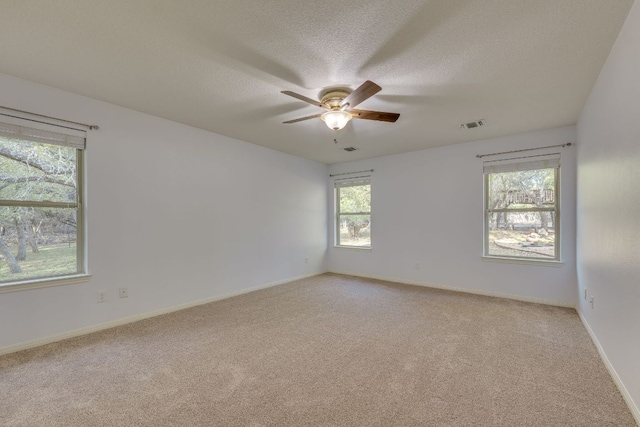 empty room featuring visible vents, baseboards, ceiling fan, light colored carpet, and a textured ceiling