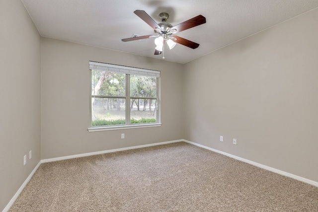 carpeted empty room with a ceiling fan and baseboards