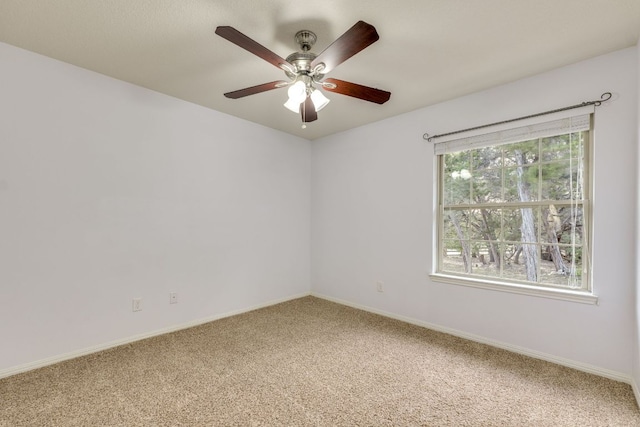 spare room with baseboards, light carpet, and a ceiling fan