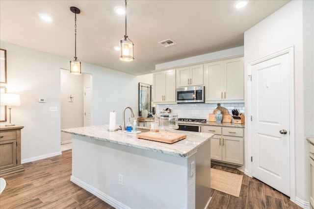 kitchen featuring decorative backsplash, stainless steel microwave, wood finished floors, and visible vents