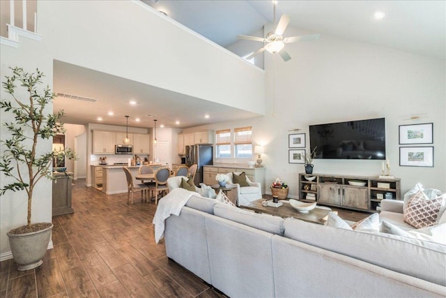 living area featuring ceiling fan, dark wood-type flooring, visible vents, and high vaulted ceiling