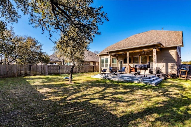 rear view of property featuring a yard, a fenced backyard, and a patio area