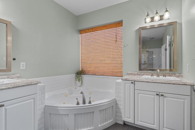 full bath with a shower, a jetted tub, two vanities, and a sink