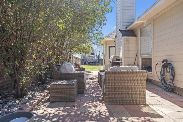 view of patio featuring an outdoor living space, a trampoline, fence, and a grill