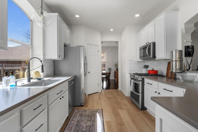 1617 Shady Hillside Pass, Round Rock, TX 78665 - kitchen featuring appliances with stainless steel finishes, white cabinetry, decorative backsplash, light wood-style flooring, and recessed lighting