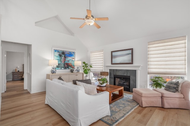 living room featuring ceiling fan, high vaulted ceiling, wood finished floors, and a tile fireplace