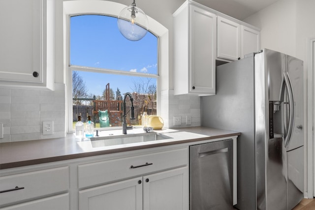 kitchen with a sink, light countertops, appliances with stainless steel finishes, white cabinetry, and backsplash