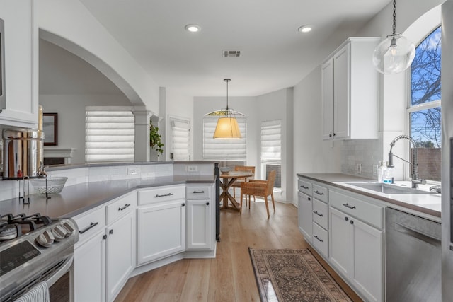 kitchen featuring visible vents, a sink, stainless steel appliances, white cabinets, and light wood finished floors