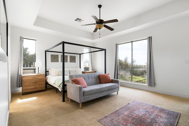 bedroom with baseboards, multiple windows, a raised ceiling, and visible vents