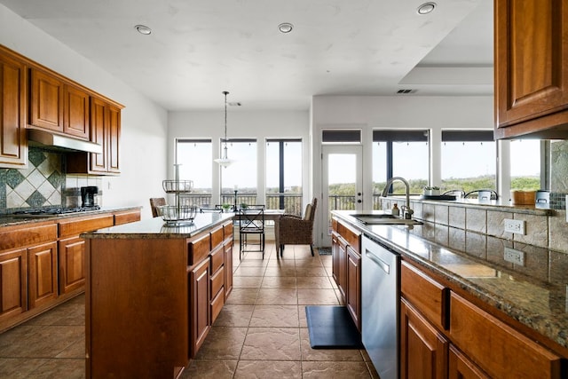 kitchen featuring under cabinet range hood, decorative backsplash, plenty of natural light, stainless steel appliances, and a sink