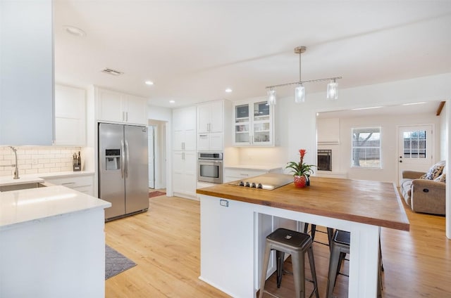 kitchen featuring light wood-style flooring, butcher block counters, stainless steel appliances, and a sink