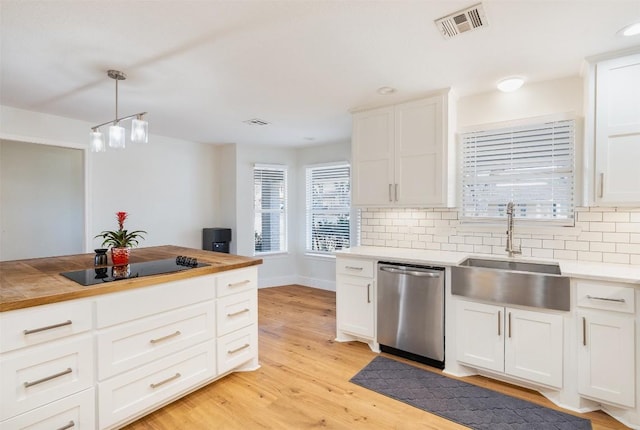 kitchen with visible vents, dishwasher, light wood-type flooring, decorative backsplash, and a sink