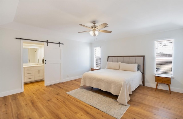 bedroom with multiple windows, light wood-style floors, and a barn door