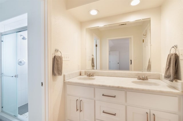 bathroom featuring double vanity, a stall shower, and a sink