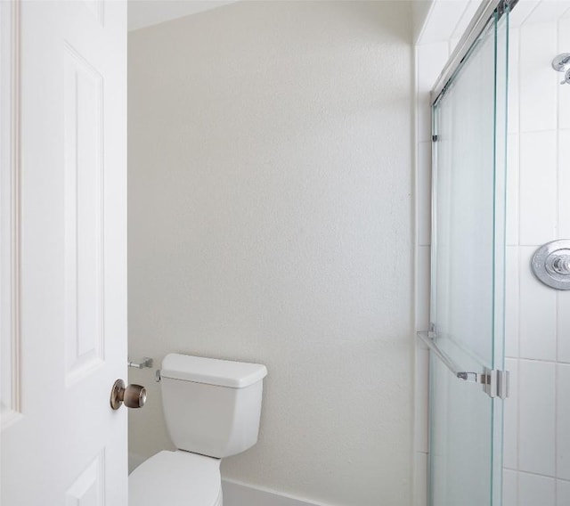 bathroom featuring a shower stall and toilet