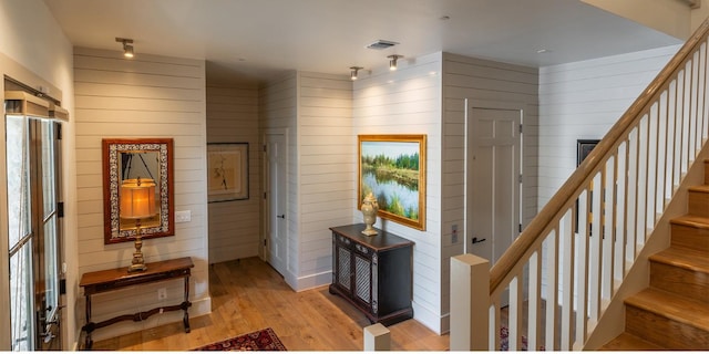 interior space with visible vents, wooden walls, light wood-style flooring, and stairway