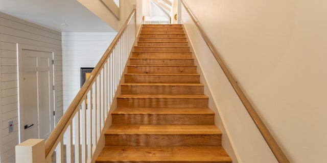 staircase featuring wooden walls