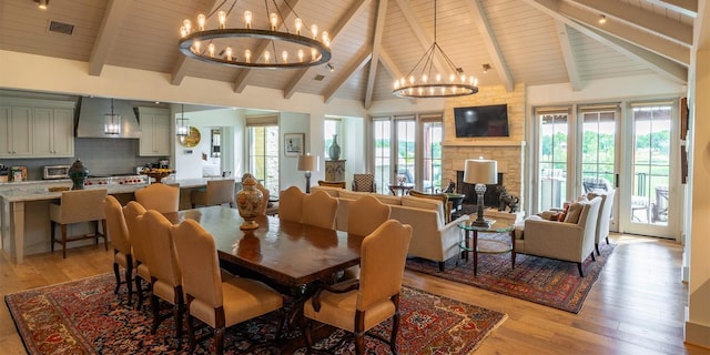 dining area with a chandelier, visible vents, beamed ceiling, and light wood-style floors