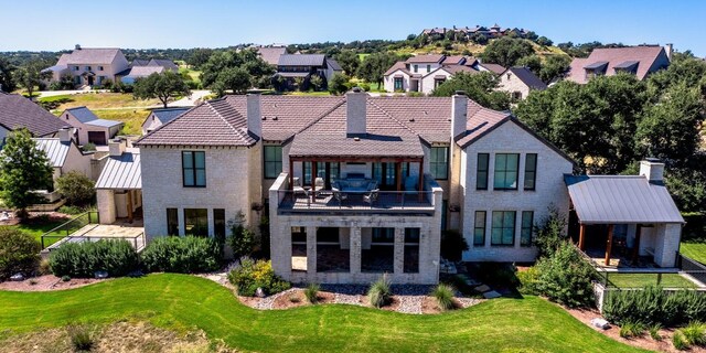 rear view of property featuring a balcony, brick siding, a residential view, and a chimney