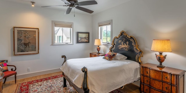 bedroom with multiple windows, a ceiling fan, baseboards, and wood finished floors