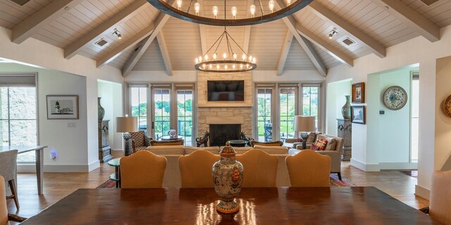 dining area with baseboards, a stone fireplace, wood finished floors, and an inviting chandelier