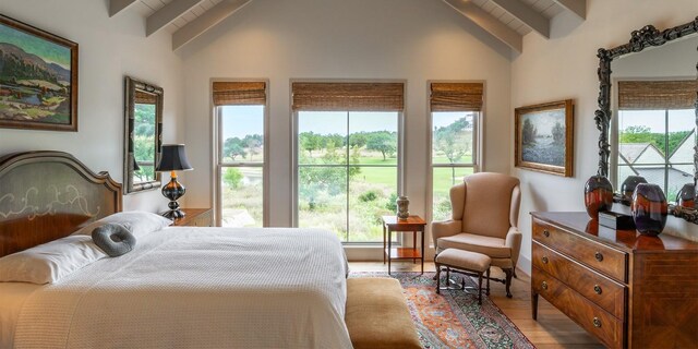 bedroom with lofted ceiling with beams and light wood-style floors