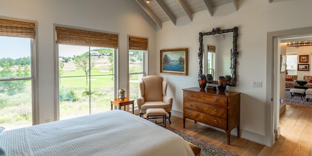 bedroom with light wood-type flooring, lofted ceiling with beams, and baseboards