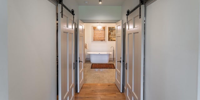 hallway featuring light wood-type flooring and a barn door