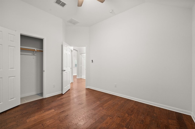 unfurnished bedroom featuring wood finished floors, visible vents, baseboards, vaulted ceiling, and a closet