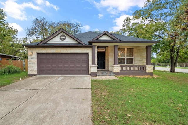 view of front of property with driveway, an attached garage, covered porch, a front lawn, and stone siding