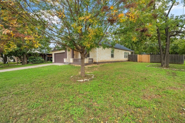 exterior space featuring a lawn, concrete driveway, a garage, and fence