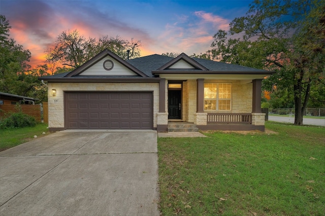 view of front of house featuring a lawn, stone siding, covered porch, concrete driveway, and an attached garage